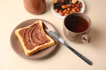Tasty toast with chocolate paste and cup of tea served on light table