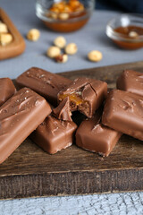 Delicious chocolate candy bars with caramel and nuts on grey wooden table