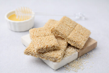 Delicious sesame kozinaki bars and honey on white table, closeup