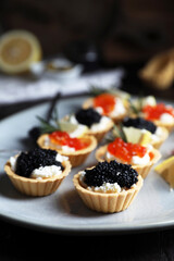 Delicious tartlets with red and black caviar served on table, closeup