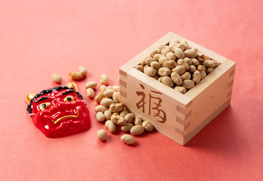 Beans for bean-throwing and masks of ogres placed on a background of red Japanese paper. Japanese ogres.