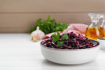 Tasty red cabbage sauerkraut with parsley on white wooden table. Space for text