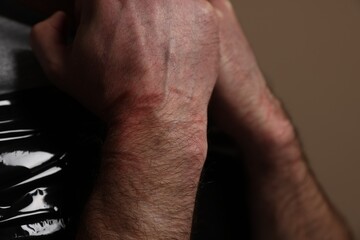 Fototapeta na wymiar Tied man with bruises on beige background, closeup. Hostage taking