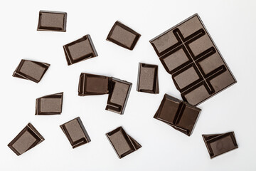 Dark chocolate bar and cubes isolated on white background, top view
