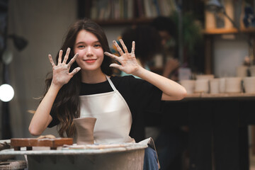 happy smiling girl having fun to learning and work with craft art of clay hand-made workshop in ceramic studio, little ceramist enjoy in creative handcraft hobby with pottery artisan school class