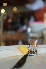 Dirty plate with leftover food and fork on a background of lights in a restaurant