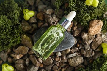 Cosmetic dropper bottle and green moss on rocks, closeup
