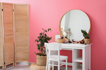 Interior of stylish makeup room with table, mirror and houseplants