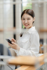 Obraz premium Asian woman talking to friend with smartphone Mobile phones and internet technology to chat online with her friends during a coffee shop visit.