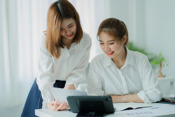 Asian serious business woman accountant using digital tablet for mathematical analysis on wooden table in office, young woman tax holding laptop Answer emails with customers