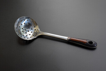 Stainless Steel Round Kitchen Skimmer or Skimmer Spoon Isolated on black Background.