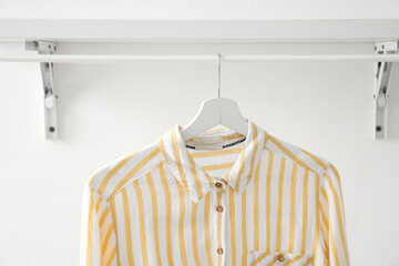 Striped shirt hanging on shelf near light wall, closeup