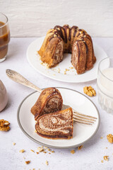 Plate with pieces of delicious cake and walnuts on light background
