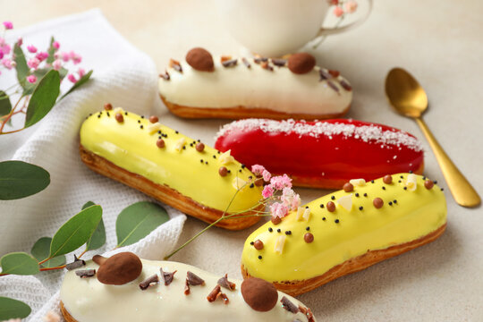 Delicious glazed eclairs and floral decor on grey background