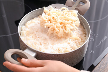 Woman cooking tasty pasta on stove, closeup