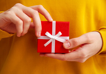 Woman in yellow sweater with gift box for Valentine's Day, closeup