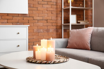 Interior of living room with burning candles on table and cozy sofa