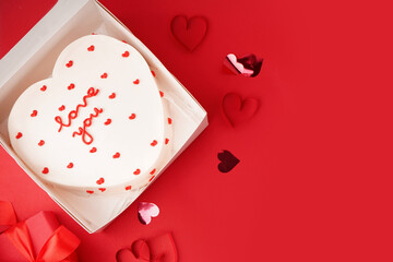 Opened box with heart-shaped bento cake on red background. Valentine's Day celebration