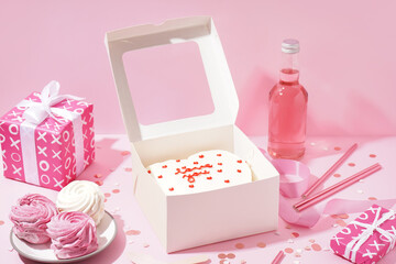 Opened box with tasty bento cake, gifts and zephyr on pink table. Valentine's Day celebration