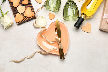 Table setting with bottle of wine, glasses, heart-shaped cookies and rose flower on white...