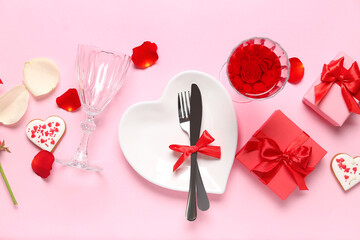 Heart shaped plate, cutlery, gifts for Valentine's Day celebration and rose petals on pink background