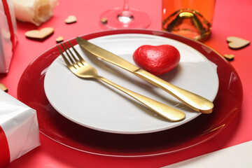 Plate with heart figure and golden cutlery on red background. Valentine's Day celebration