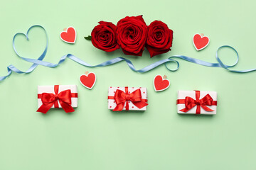 Rose flowers, gifts and heart made of blue satin ribbon on green background. Valentine's Day celebration