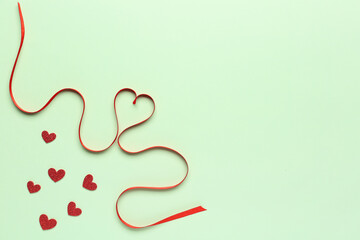 Heart made of red satin ribbon on green background. Valentine's Day celebration