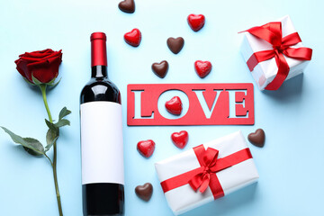 Bottle of wine, word LOVE, chocolate candies, gifts and rose flower on blue background. Valentine's Day celebration