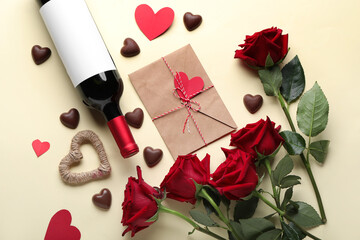 Bottle of wine, chocolate candies, envelope and rose flowers on beige background. Valentine's Day celebration