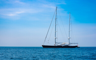 large luxury sailing yacht is anchored off an island in a tropical sea.