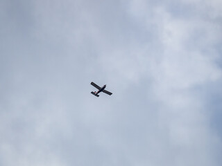 Small ultralight airplane with overhead wing and single propeller flying in sunset sky.