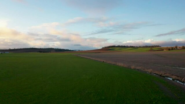 Aerial flight over mixed use land in Willamette Valley, Oregon, near Monmouth.  Very green fields, barren field, winter vineyard, snowy hills in distance