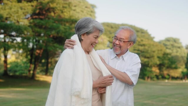 Asian senior couple wears or cover a blanket in the public garden, Elderly retirement family taking care of each other and outdoor concept