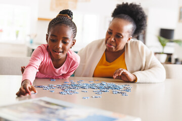 Happy african american grandmother and granddaughter doing puzzle