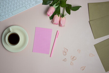 Pink letter along with pink roses and pen including coffee cup and brown envelop.