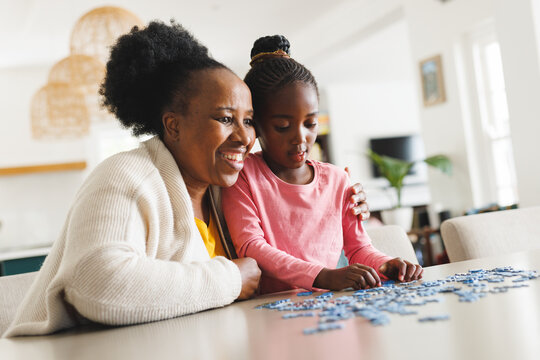Happy african american grandmother and granddaughter doing puzzle