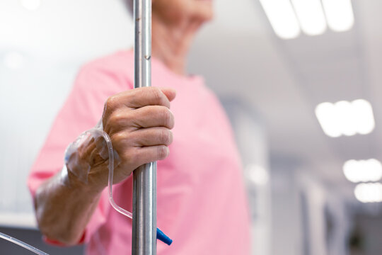 Close Up Of Senior Caucasian Female Patient Walking With Drip In Hospital Corridor