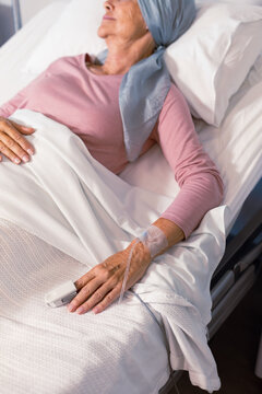 Senior caucasian female cancer patient wearing head scarf in bed with pulse oximeter at hospital