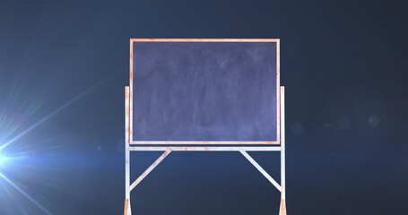 Composite of black board with copy space and glowing blue light on blue background