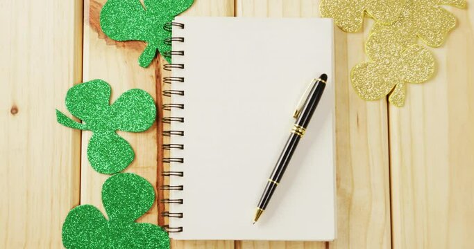 Video of st patrick's green shamrock and notebook with copy space on wooden background