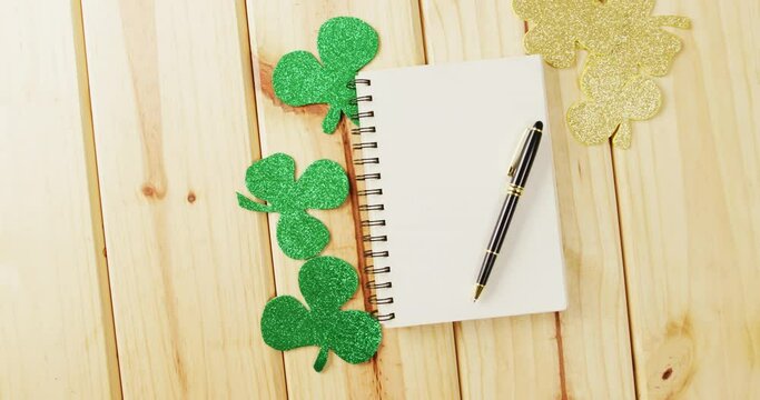 Video of st patrick's green shamrock and notebook with copy space on wooden background