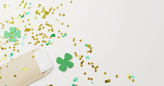 Video of st patrick's green shamrock leaves and sequins with copy space on white background