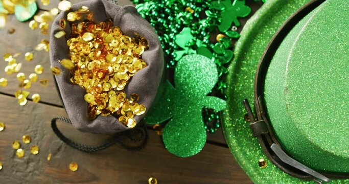 Video of st patrick's green hat, shamrock and gold sequins on wooden background
