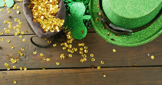 Video of st patrick's green hat, shamrock and gold sequins on wooden background