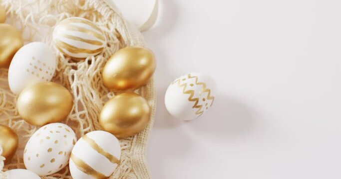 Bag with white and gold easter eggs on white background with copy space