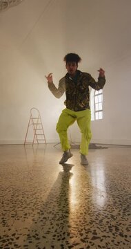 Vertical video of portrait of happy biracial male dancer dancing in dance studio