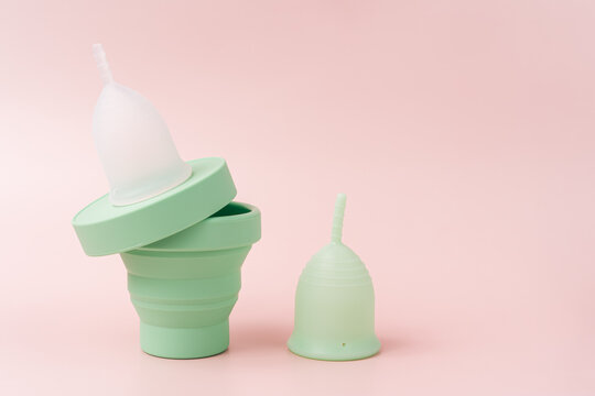 Menstrual cups with a case against a pink background.