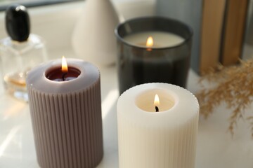 Fototapeta na wymiar Different burning candles on white table. Decoration element