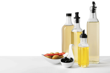 Bottles of different cooking oils and olives on white background